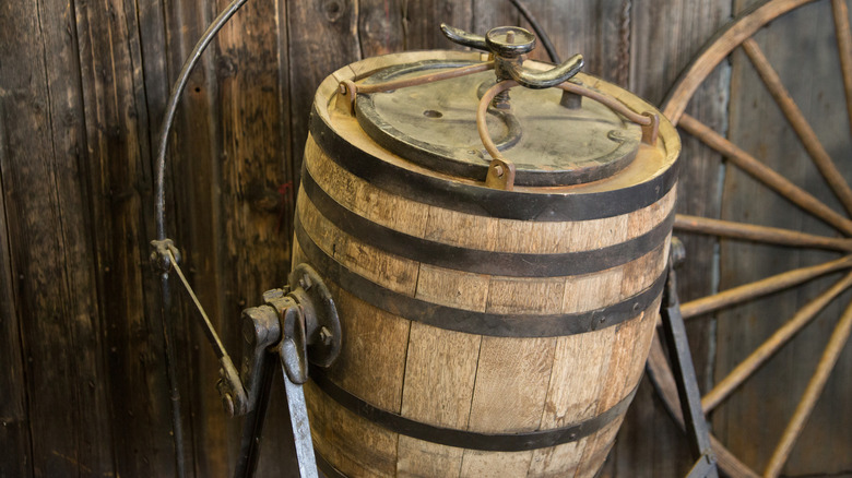antique wooden butter churn in front of wagon wheel