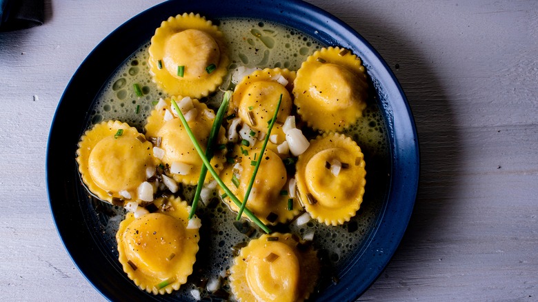 Lobster ravioli presented on a dark blue plate