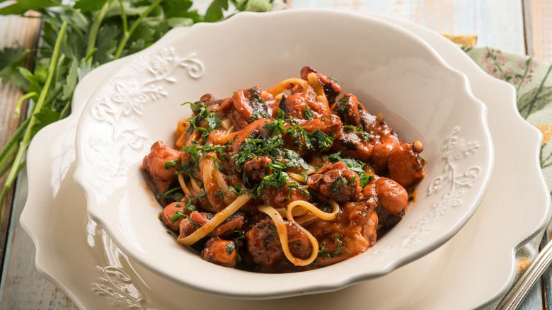 Octopus pasta served in a white bowl with parsely at the side