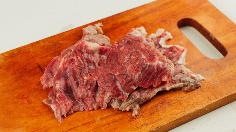 Mushy, raw steak on a wooden cutting board