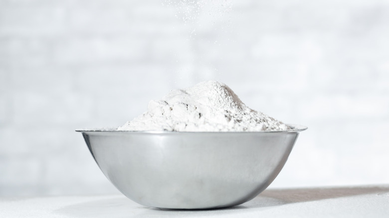 White flour is piled in a metal bowl.