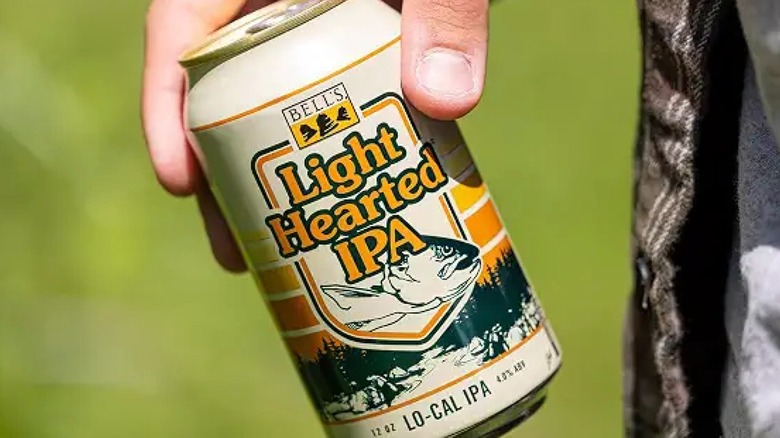 Hand holding a can of Bell's Light Hearted IPA over a kayak on a lake