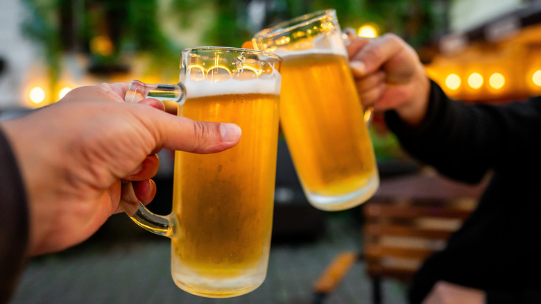 Hands toasting two steins of light beer