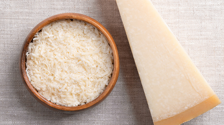 Grated parmesan cheese with a solid piece of the cheese