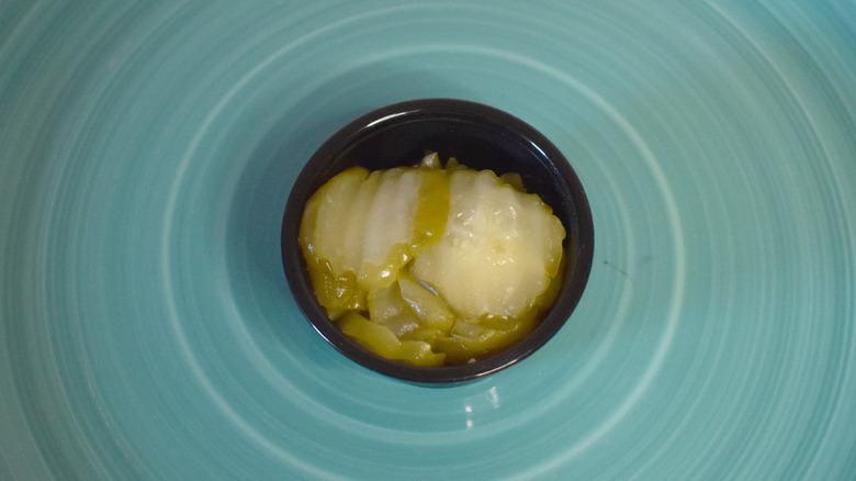 A small black plastic cup of Wendy's pickles on a blue plate