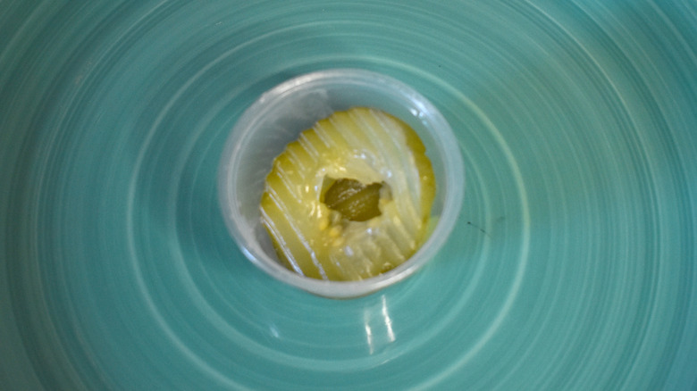 A small cup of Chick-fil-A pickles on a blue plate