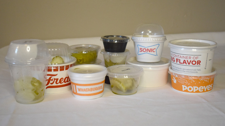 A selection of different containers filled with fast food pickles from various chains