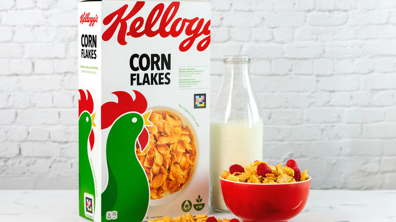 A box of Kellogg Corn Flakes next to a bowl of corn flakes with milk