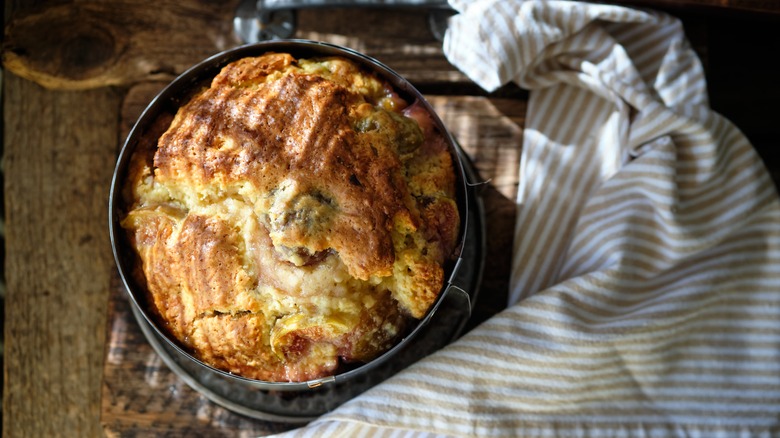 A rustic fig cake in a metal dish besides a striped towel