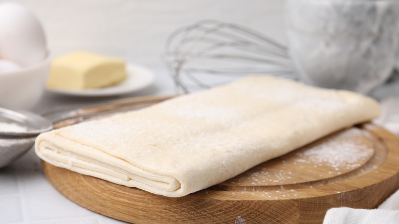Raw puff pastry on a wooden cutting board