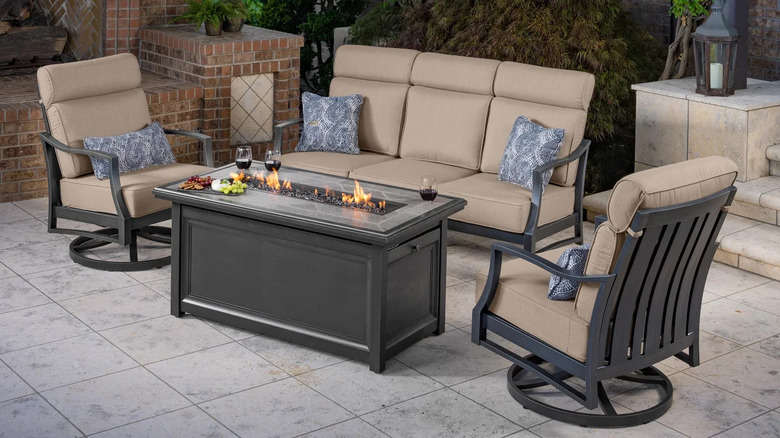 A patio set with a lit fire table with drinks and snacks