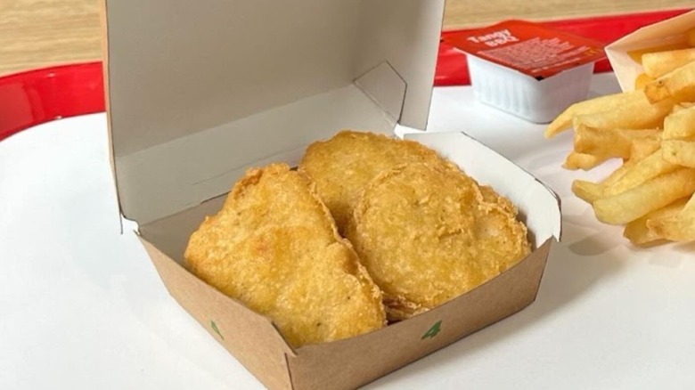 Chicken McNuggest on a tray with fries and dipping sauce in the background