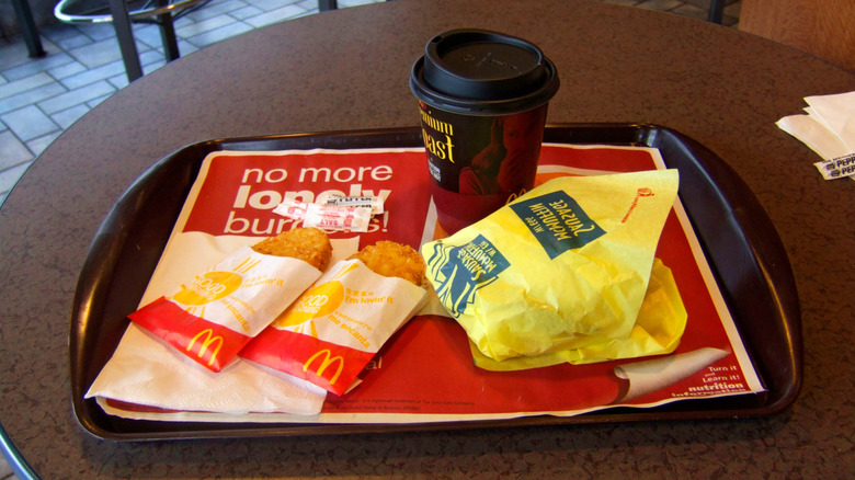 Two McDonald's hash browns, a coffee, and breakfast sandwich on a tray