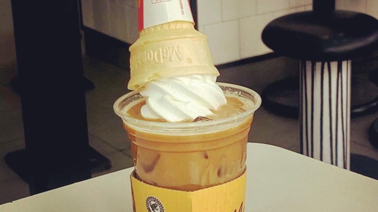 A McDonald's iced coffee with an ice cream cone dunked in it