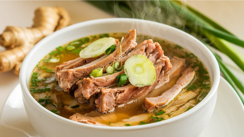 A bowl of bak kut teh soup garnished with green onions