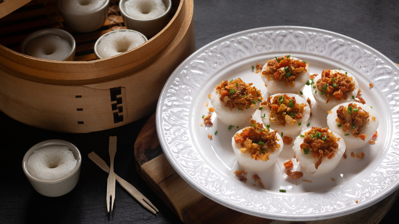 A plate of chwee kueh next to a bamboo steamer
