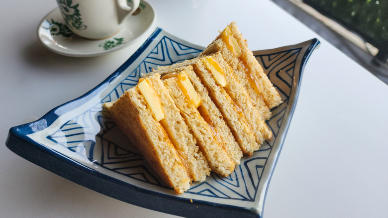 A plate of kaya toast next to a cup of coffee