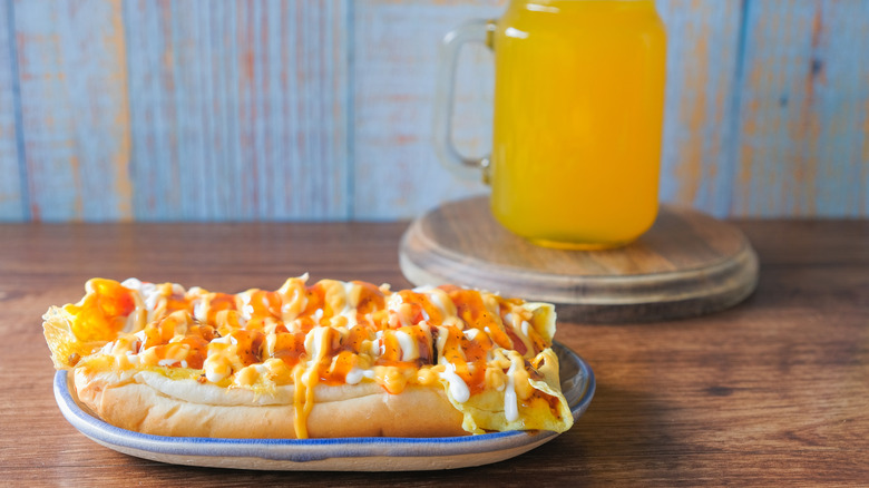 A roti John sandwich on a plate next to a glass of juice