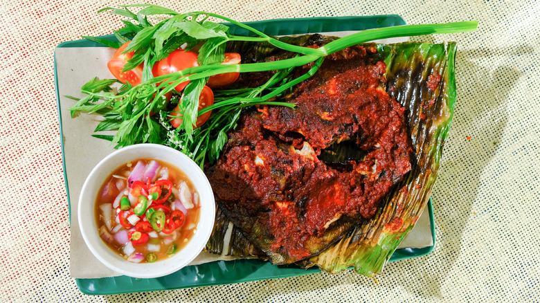 Barbecued stingray on a plate with a dish of sambal