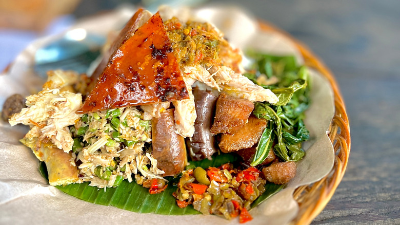 plate of babi guling with pork meat, crispy skin, vegetables, and rice