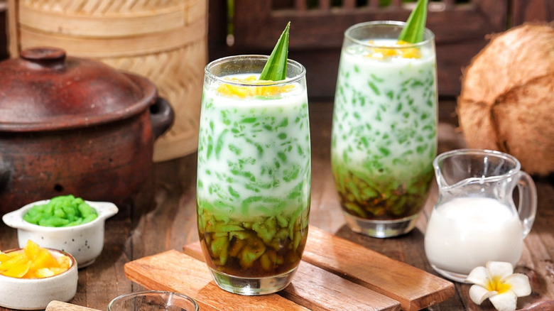 Two glasses of es cendol on a wooden table