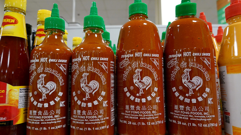 Four bottles of Sriracha on a store shelf