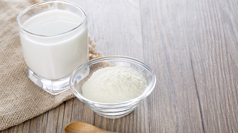 Powdered milk with glass of milk and a spoon