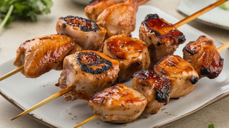 Yakitori skewers with tare glaze on a square ceramic plate