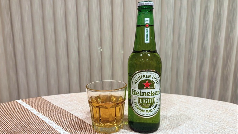 A glass of Heineken Light next to a bottle of Heineken Light
