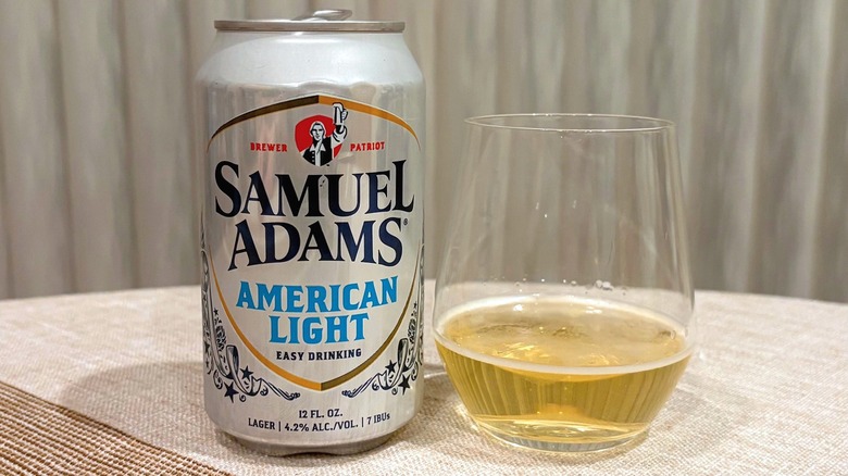 A can of Samuel Adams American Light beer next to a glass of it