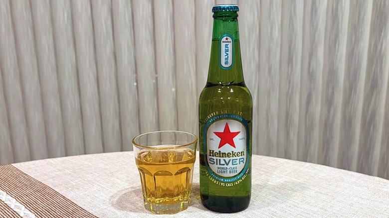 A glass of Heineken Silver next to a bottle of Heinekin Silver