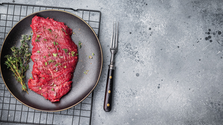 A raw marinated flank steak resting on a plate