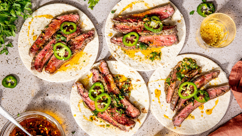Tacos with flank steak, jalapeños and chimichurri sauce on a table