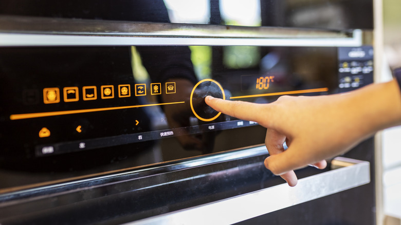 A person setting the temperature on an oven