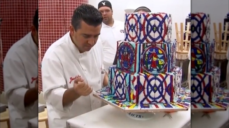 The Cake Boss piping icing on a stained glass-themed cake