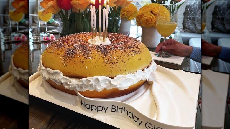 A bagel cake with a birthday banner on a white display tray