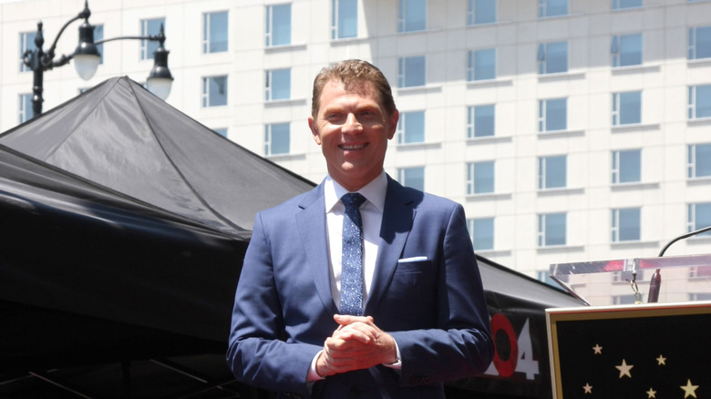 Bobby Flay smiles while wearing a blue suit