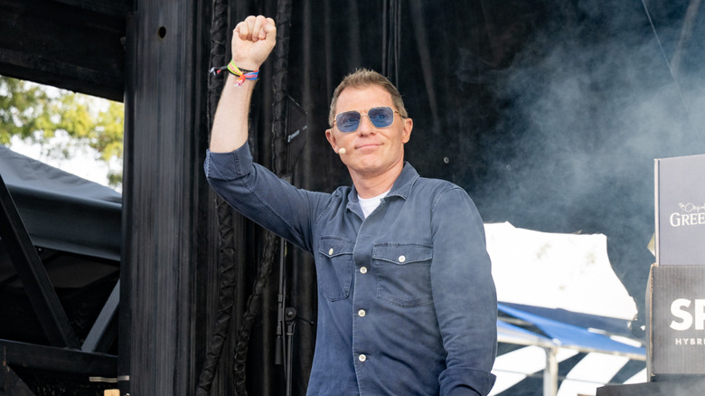 Bobby Flay poses on stage at a cooking demonstration