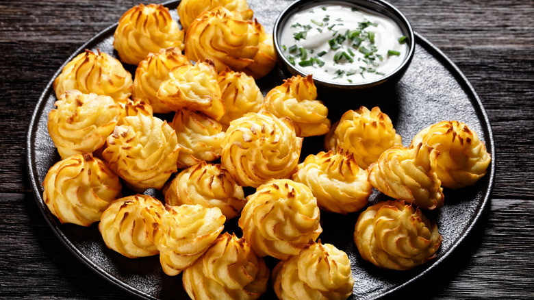 A plate of duchess potatoes with dipping sauce