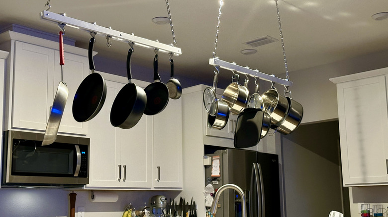 Pots and pans hanging from two racks in a gourmet kitchen