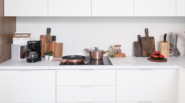 White kitchen with cooking ingredients store near stove and coffee stored near coffee maker