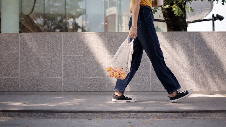 Person carrying reusable produce bag walking
