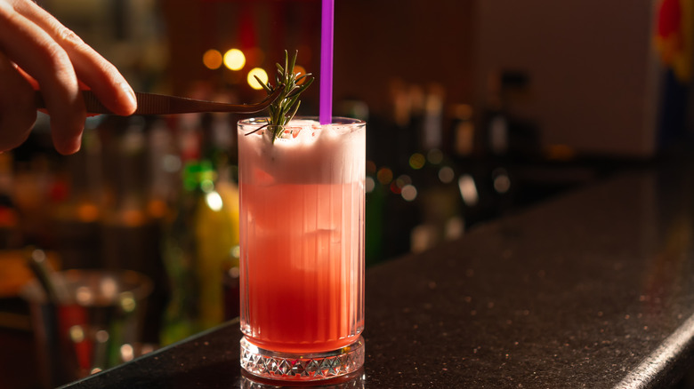 Bartender garnishing cocktail with red wine foam