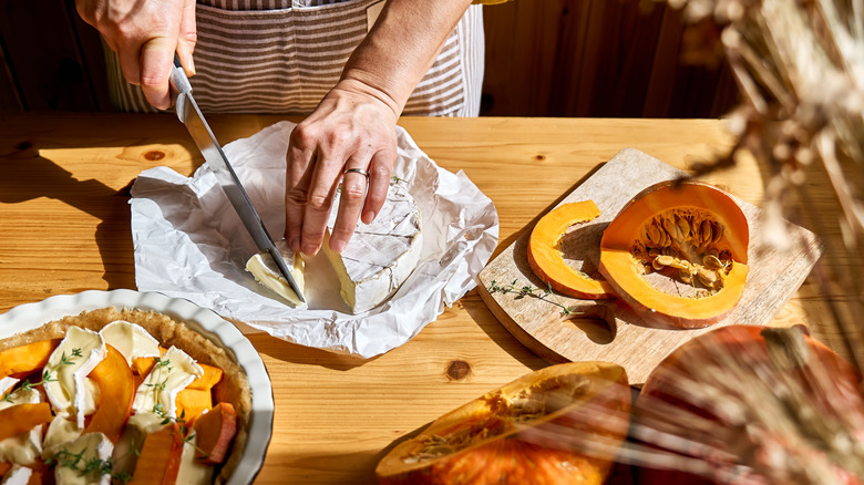 Person assembling a pumpkin baked Brie