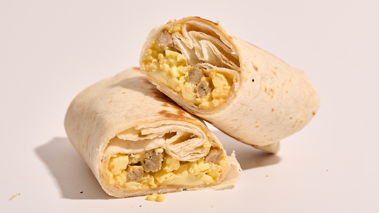 sausage breakfast burrito sliced in half on a white table