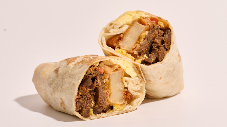 steak breakfast burrito sliced in half on a white table