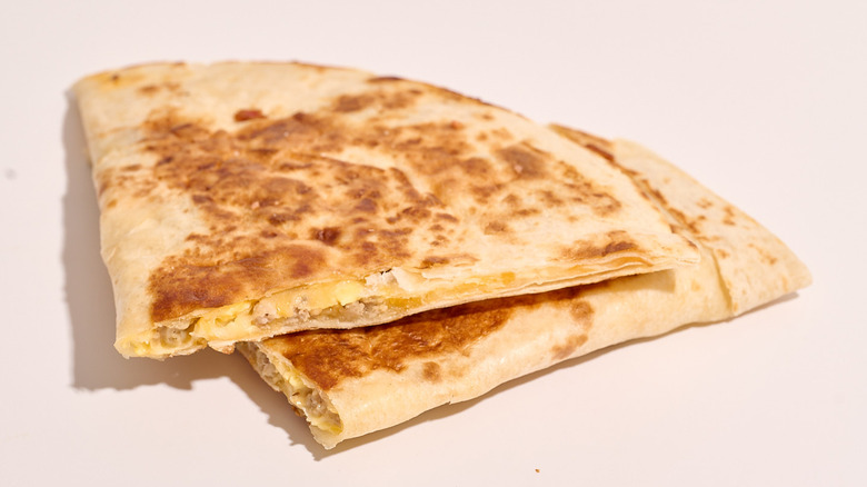 sausage and cheese quesadilla cut in half on a white table