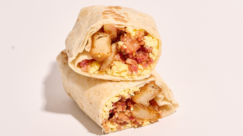 grande bacon breakfast burrito sliced in half on a table
