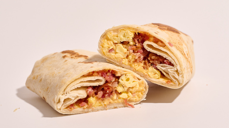 bacon breakfast burrito sliced in half on a white table