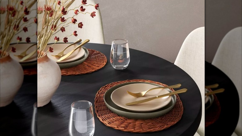 Rattan placemats under flatware on black wood table.